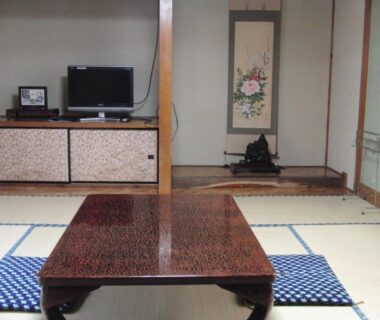 Traditional tatami room with low lacquered table, zabuton cushions and tokonoma alcove at Tajimaya in Gifu, Japan