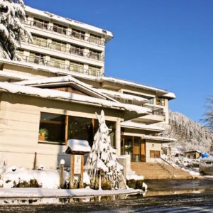 Takahan entrance and snow-covered facade with parked cars beneath a clear blue sky in Niigata