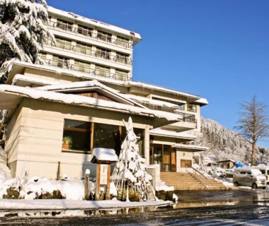 Takahan entrance and snow-covered facade with parked cars beneath a clear blue sky in Niigata