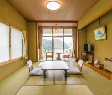 Traditional tatami room with low table, seating cushions and mountain valley view at Takahan, Niigata