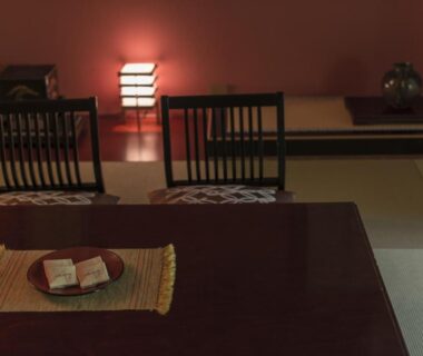 Low-lit tatami room with low table, cushions, wooden chairs and tray of sweets at Takamiya Bettei Kuon, Yamagata