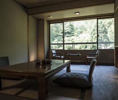 Japanese tatami room with low table and cushions, window overlooking trees at Takamiya Bettei Kuon Yamagata Tōhoku