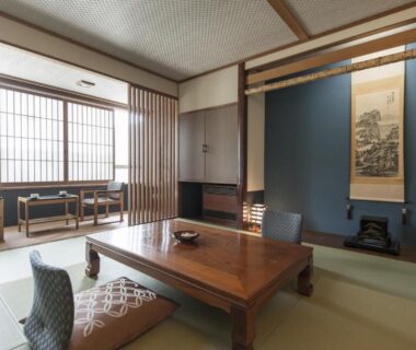 Traditional tatami room with low table, floor chairs, shoji screens and tokonoma scroll at Takamiya Bettei Kuon, Yamagata