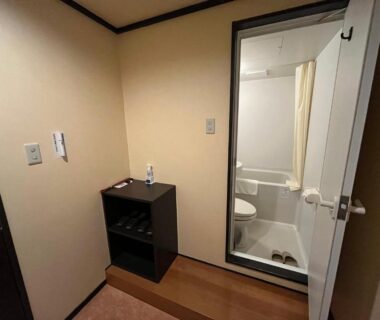 Small genkan and compact bathroom with glass door at Takamiya Hotel Lucent in Yamagata Tōhoku