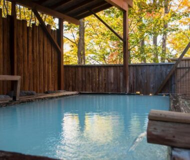 Milky blue outdoor onsen with wooden fence and autumn trees at Takamiya Hotel Lucent, Yamagata Tōhoku