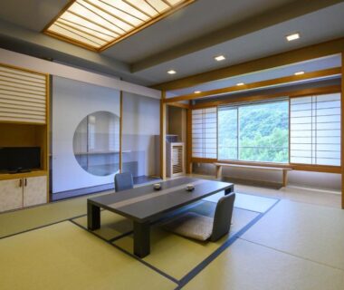 Traditional tatami room with low table, shoji screens, and window overlooking green hillside at Takamiya Hotel Lucent, Yamagata