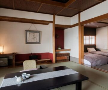 Tatami seating area with low table, tea set, shoji screens and twin beds at Takamiya Ryokan Miyamaso, Yamagata