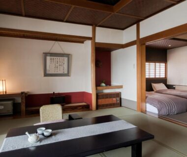 Tatami seating area with low table, tea set, shoji screens and twin beds at Takamiya Ryokan Miyamaso, Yamagata