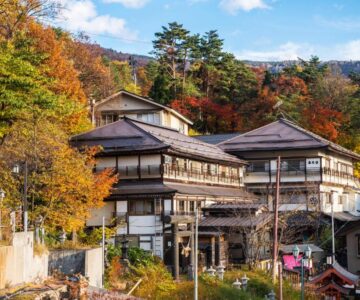 Multi-story wooden ryokan exterior amid autumn hills in Yamagata, Tōhoku