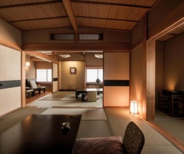 Spacious tatami room with low table, shoji screens, wooden beams and soft lantern lighting at Takamiya Ryokan Miyamaso in Yamagata