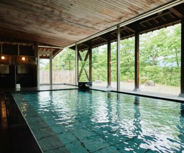 Tiled indoor onsen with wooden ceiling and large windows overlooking garden at Takamiya Ryokan Sagiya Sansorai Yamagata