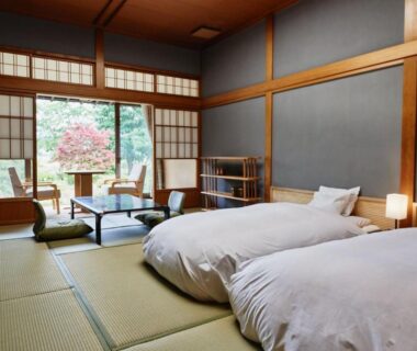 Tatami room with low beds, shoji screens and table, sliding doors to garden at Takamiya Ryokan Sagiya Sansorai Yamagata
