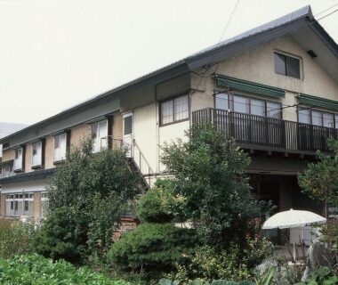 Two-story ryokan building with wooden balconies and lush garden at Takanoya, Niigata, Chūbu, Japan