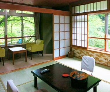 Traditional tatami room with low table, shoji screens and garden view at Takao Kanko Hotel in Kyoto