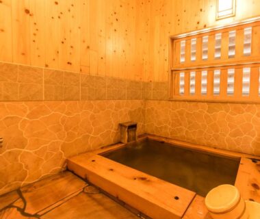 Indoor wooden soaking bath with tiled walls and bucket at Takaosou, Ōita, Kyushu