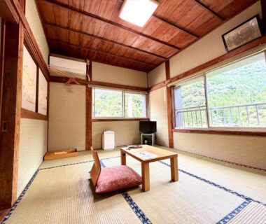 Tatami mats, low table and cushion in Takaosou room with wooden ceiling and mountain view, Ōita, Kyūshū