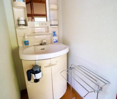 Small vanity sink with mirror, soap dispensers and towel rack in Takaosou bathroom, Ōita