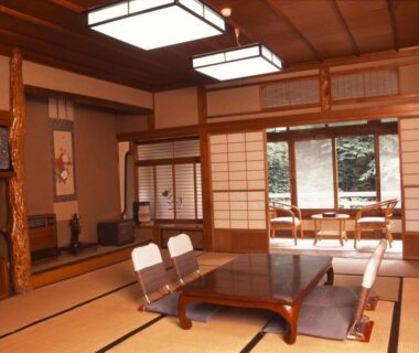 Traditional tatami room with low table, legless chairs and shoji screens overlooking a garden at Takaragawa Onsen Ousenkaku, Gunma