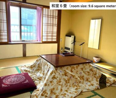 Tatami room with kotatsu table, shoji-style window and floor cushion at Takasagoya Ryokan in Yamagata
