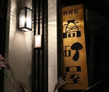 Illuminated wooden signboard with Japanese characters by a lantern at Takasagoya Ryokan entrance in Yamagata, Tōhoku, Japan