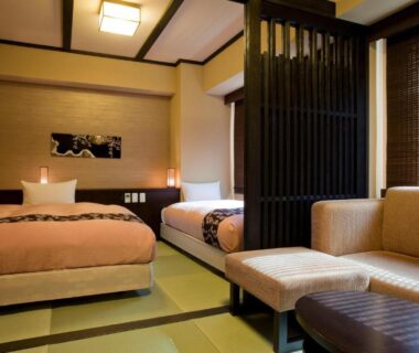 Tatami room interior with twin beds, wooden partition and sofa seating at Takayama Ouan in Gifu
