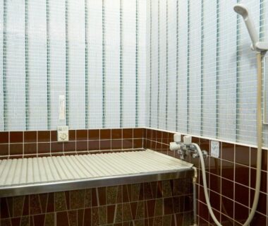 Tiled bathtub with cover and showerhead at Takeyaso Ryokan in Hyōgo, Kansai