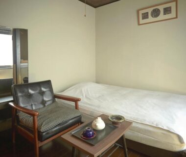 Simple room with futon, wooden chair and low tea table at Takeyaso Ryokan in Hyōgo, Kansai