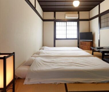 Three futons on tatami floor, shoji window, low table and lantern lighting at Takeyaso Ryokan, Hyōgo, Japan