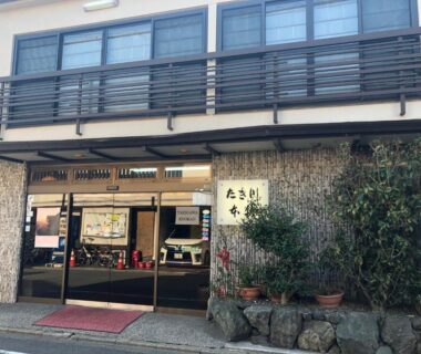 Entrance facade of Takigawa Ryokan with glass sliding doors and stone planter in Kyoto