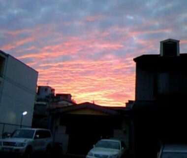 Evening pink sky above silhouetted buildings and parked cars at Takigawa Ryokan, Kyoto
