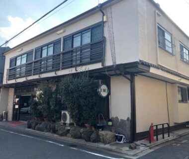 Street-facing two-story exterior of Takigawa Ryokan with small shrubs and balcony in Kyoto, Kansai, Japan