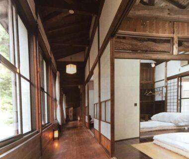 Long wooden corridor with shoji screens and tatami room with futons at Takimi Onsen Inn, Nagano, Chūbu