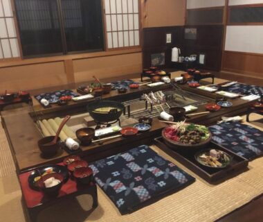 Low tatami dining with trays, zabuton cushions and shoji screens at Takimi Onsen Inn Nagano