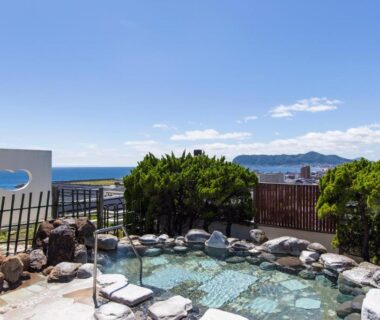 Stone outdoor onsen pool overlooking coastal Hokkaidō ocean near Takuboku Tei