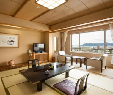 Traditional tatami room with low table, zabuton cushions, chairs and large window view at Takuboku Tei, Hokkaidō