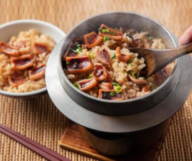 Steaming mushroom rice served in a small pot with wooden spoon and bowls at Takuboku Tei, Hokkaido, Japan