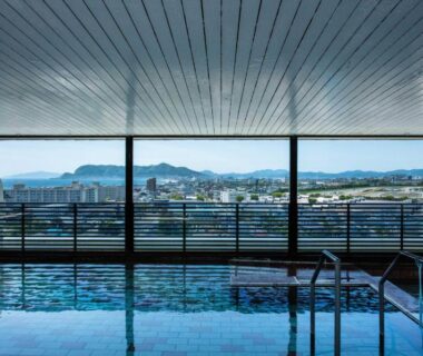 Indoor onsen bath with large windows overlooking city and mountains at Takuboku Tei, Hokkaidō
