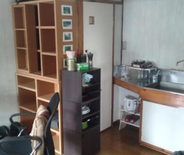 Compact guest room with desk, shelving and kitchenette at Tama Ryokan in Tokyo, Kantō
