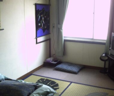 Small tatami room with futon and cushions at Tama Ryokan, Tokyo