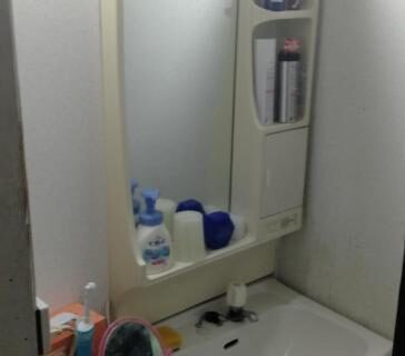 Sink with mirror cabinet, toiletries and towel in compact bathroom at Tama Ryokan Tokyo
