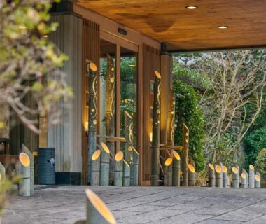 Stone entrance path with low lantern lights and wooden eaves at Tamana Onsen Happouen, Kumamoto, Kyūshū, Japan