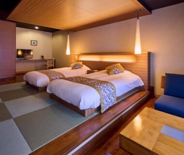 Tatami-floored twin room with raised beds and low table at Tamana Onsen Happouen in Kumamoto, Kyūshū