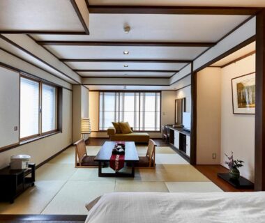 Spacious tatami room with low table, futon bed, shoji screens and seating area at Tamaya Ryokan in Nagano