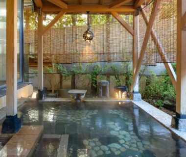 Covered onsen with wooden beams, bamboo blinds and stone floor at Tamaya Ryokan in Nagano, Chūbu