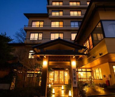 Evening exterior of Tamaya Ryokan with illuminated entrance and warm lit windows in Nagano, Chūbu