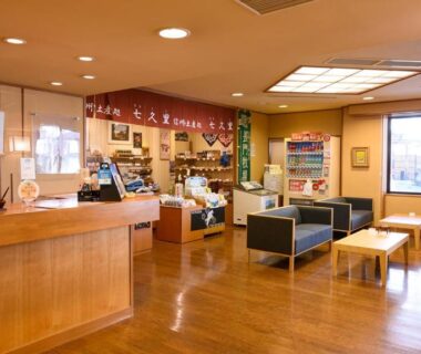 Reception area with wooden desk, seating sofas, brochures and large windows at Tamaya Ryokan, Nagano