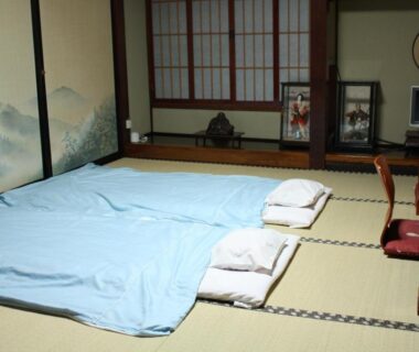 Tatami room with laid futon, shoji screens and low desk at Tamonkan in Yamagata