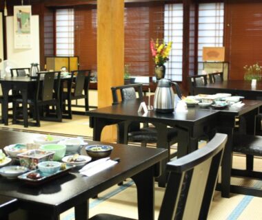 Low black tables on tatami with multiple small dishes and wooden interior at Tamonkan, Yamagata