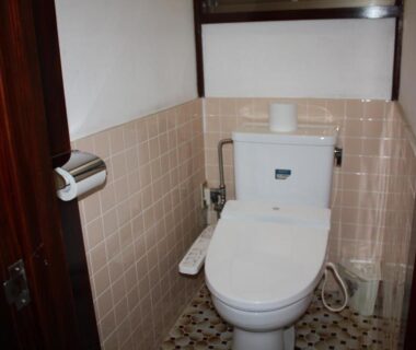 Western style toilet with bidet controls, tiled walls and patterned floor at Tamonkan Ryokan Yamagata Tōhoku