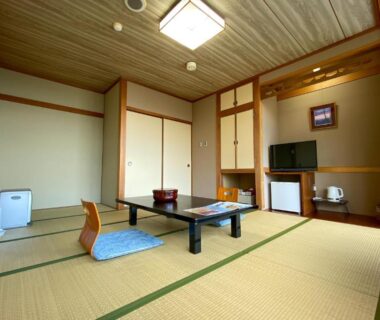 Tatami room with low table, floor cushions, shoji screens, TV and kettle at Tango Onsen Hashiudosou Kyoto